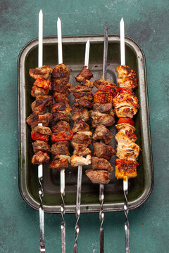 Skewers kebab filled with pork and chicken sit on a tray.