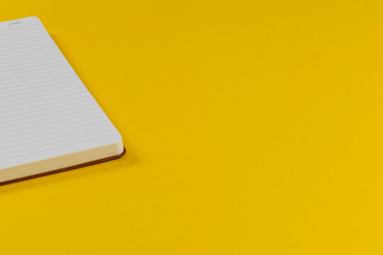 Blank notebook on yellow surface for writing notes and planning tasks