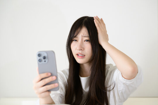 スマートフォンを見て悩む日本人女性
