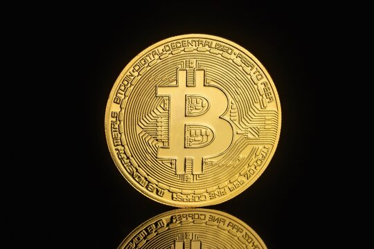 Bitcoin coin rests on a dark surface to symbolize the growth of digital currency markets and decentralized electronic assets as a modern financial investment tool for traders in the global economy.