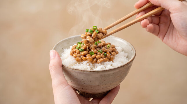 温かい白米に載せた納豆ご飯を箸で持ち上げる手元 糸を引く納豆と立ち上る湯気