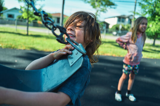 Close-up of a boy gripping the edge of a playground swing seat