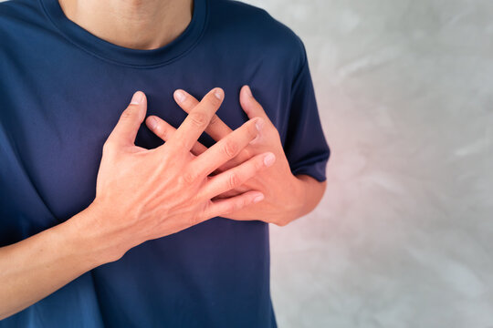 hand hold chest with heart attack symptoms, man have chest pain caused by heart disease, leak, dilatation, enlarged coronary heart, press on the chest with a painful expression