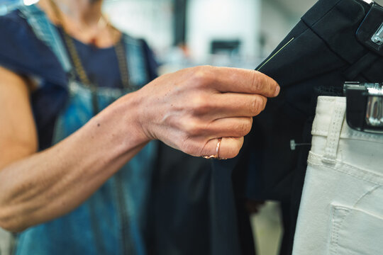 Close-up of a hand inspecting fabric on a clothing rack