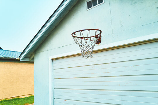 Rusty basketball hoop with torn net mounted on a garage wall