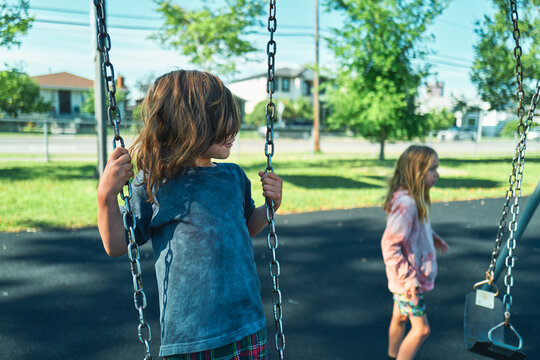 Two boys standing at chain swings in a suburban playground