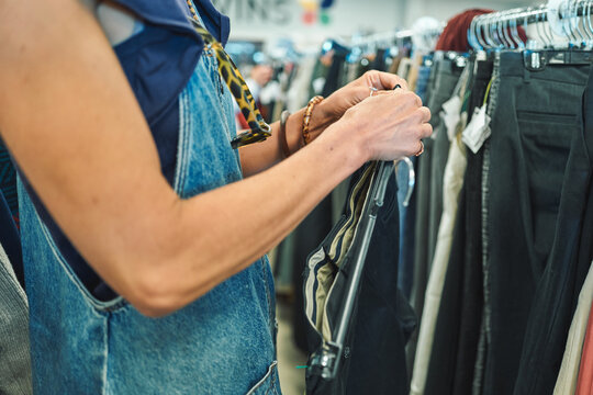 Woman browsing pants on a clothing rack at a thrift store