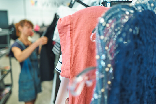 Clothing rack with a woman shopping out of focus in the background