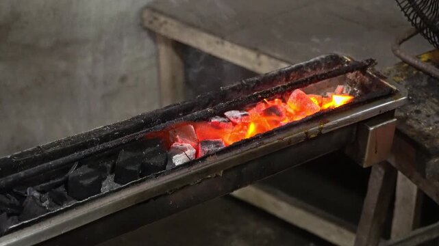 Traditional Indonesian chicken satay skewered on bamboo sticks, grilling and sizzling over glowing hot charcoal coals at a local street food stall.