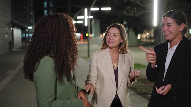 Three elegant business women talking in the city at night