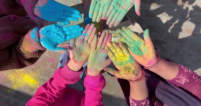 Group of friends showing their colorful hands stained with organic powders for holi festival.