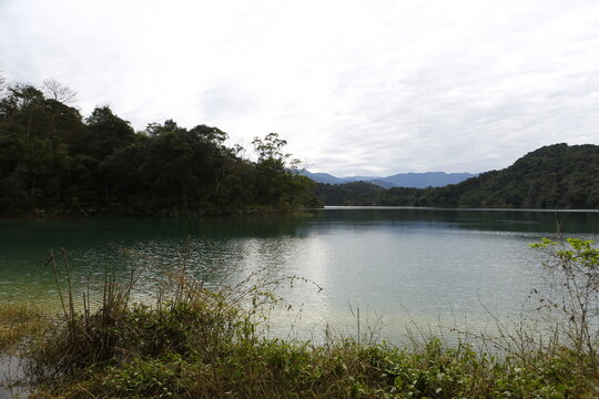Calm lake water surrounded by lush mountains.
