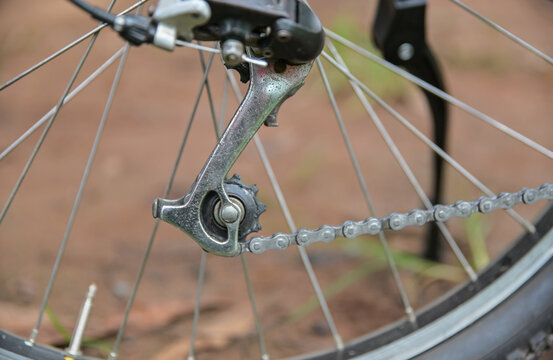 Close-up of a vintage bicycle rear derailleur and chain mechanism with wheel spokes background.