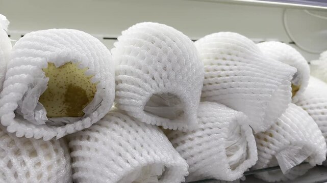 Fresh Fruits Wrapped in White Foam Net Sleeves on Supermarket Shelf