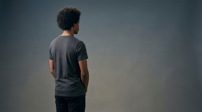 Man, back view and black guy standing in studio with copy space, advertising and marketing mock up. African American, person and casual clothes with hair, dark grey t-shirt and rear look alone.