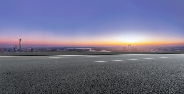 Empty Asphalt Road Leading to Distant City Skyline at Dawn