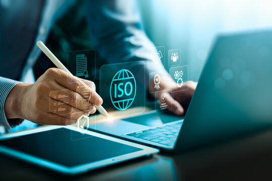 ISO certification and digital compliance concept with businessman hand using stylus on tablet laptop, quality management system, standardization, assurance, governance, audit, approval, reliability