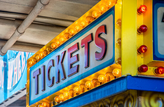 A vibrant pop of nostalgia: this bright yellow, vintage-style marquee sign glows with warm, illuminated bulbs framing the classic word "TICKETS."