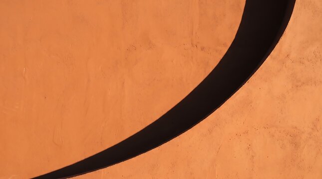 Bold curved shadow across a warm terracotta textured surface creating a minimalist abstract composition with dramatic contrast