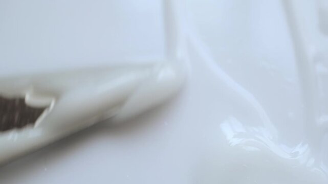 Spatula spreading white cosmetic cream in smooth, satisfying motion 