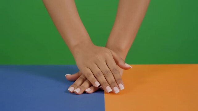 Hands interlocking during a collaborative effort against a colorful background with natural lighting