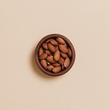 Whole raw almonds in a dark wooden bowl on a beige background with copy space, earthy and tactile for healthy snack packaging