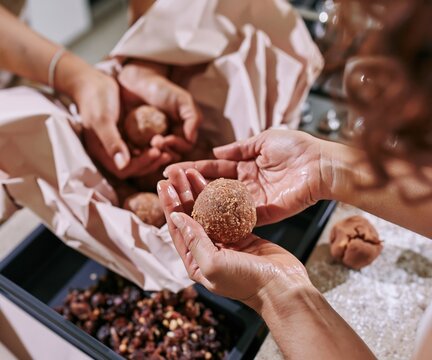Close up of hands rolling traditional besan laddoo sweets for a Diwali gift hamper, the oily palms and crumbly textures reflecting warm festive light for food packaging design