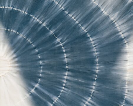 Indigo blue shibori tie dye fabric with hand-dyed resist patterns and slubbed cotton texture for textile design and apparel backgrounds