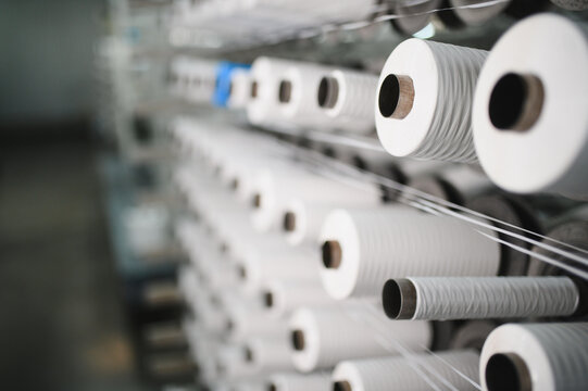 White yarn spools moving on textile production machine
