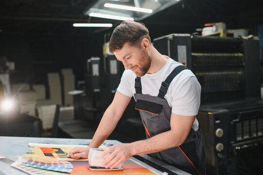 Print worker checking color quality on paper