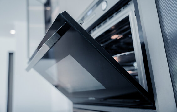 Open stainless oven interior with tray, clean metal rack and reflective glass door, warm lighting