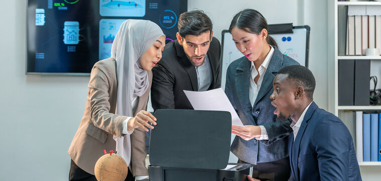 Group of four business diverse people are gathered around a printer, looking at a document has just been printed. They are all smiling and appear to be happy and excited.