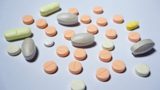 Close up of several tablets and capsules on white surface. Medical equipment. 