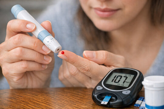 A woman checking her blood glucose levels using a glucose monitor, possibly indicating diabetes management.