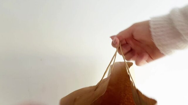 Person's hand receiving a paper bag from a delivery person on a white background, symbolizing fast food service, takeout convenience, and contactless transaction
