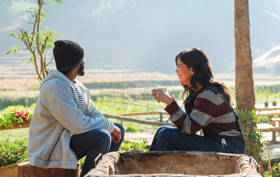 Couple sits beside a rustic wooden barrel