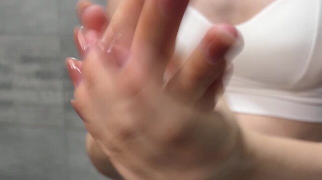 Woman with manicured nails applying moisturizing hand cream for skincare, beauty, and wellness. Close up of delicate hands performing a self care ritual in a bathroom