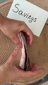 Person's hands counting turkish lira and us dollar bills and putting them into a savings envelope, showing financial planning and international currency exchange concept