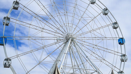 A majestic Ferris wheel stands tall against a clear blue summer sky © SGr