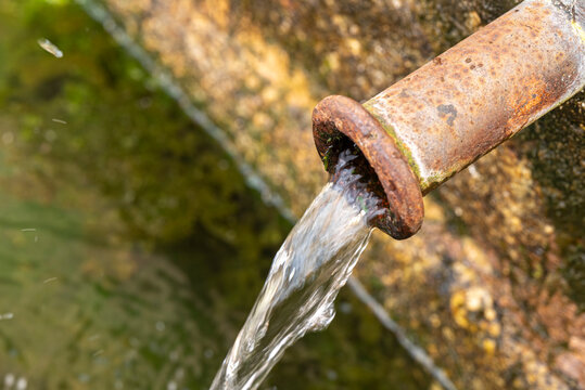 Fresh clean water flowing from rusty iron pipe The Concept of purity and life
