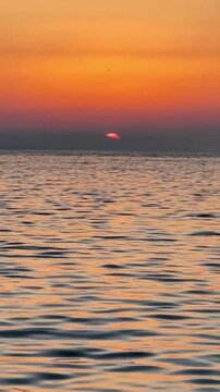 Sunset Over Calm Ocean Waves With Silhouetted Birds Flying