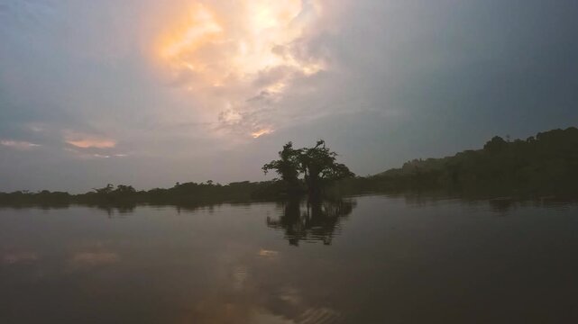 Calm Amazon River at Sunset in Ecuador with Dark Forest Reflection, Cloudy Sky, Warm Light and Remote Tropical Wilderness Landscape