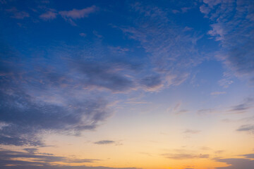Obraz premium Dramatic Altocumulus Clouds at Sunset with Warm Golden Light and Blue Sky,A breathtaking view of a dramatic altocumulus cloudscape illuminated by the warm golden light of a setting sun against a soft 