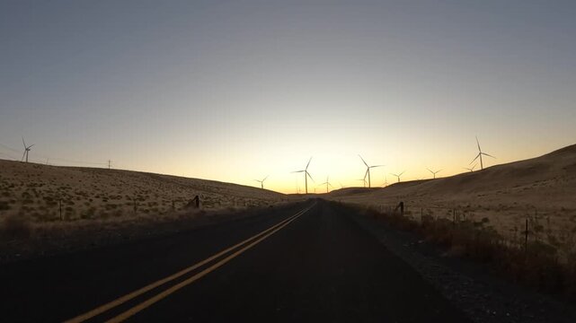 4K action camera driver's point of view of a wind farm near Arlington, Columbia River Gorge, Oregon, USA at morning light. Rotating wind turbines producing clean renewable electricity in strong winds