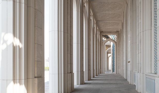 Long symmetrical corridor with tall white columns and arches perspective of Nursultan mosque