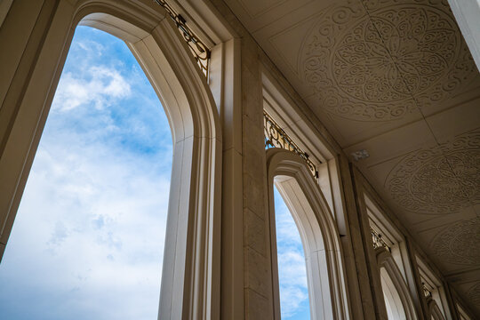 Looking up through ornate white stone arch columns toward blue sky, Islamic architecture concept
