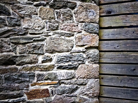 Split background of an old stone wall next to wooden planks