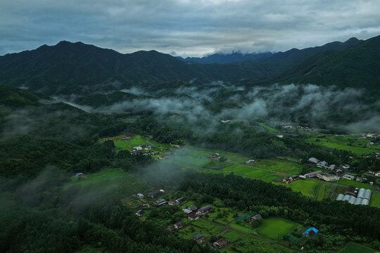 Aerial drone photo of misty mountain valley with farmland at sunrise in Mie, Japan
