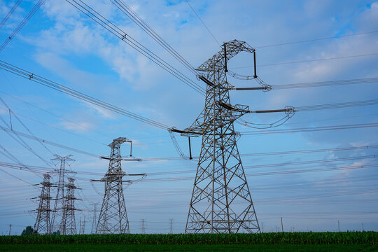 High voltage transmission tower, power pylon against cloudy blue sky