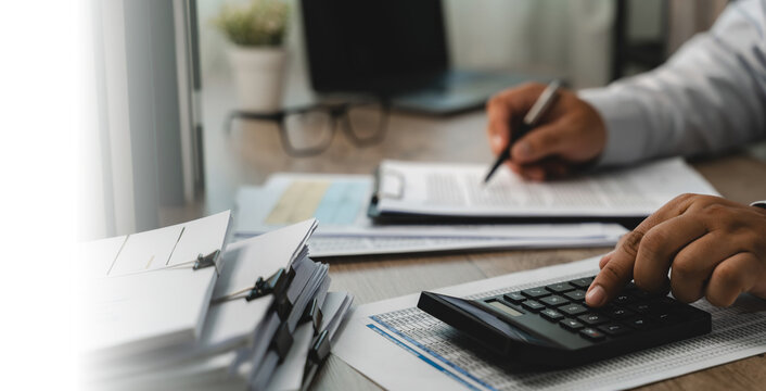 businessmen signing contract calculator on financial sheet another hand holds pen documents at desk, checking budget planning, cost calculation, expense review in office daylight.
